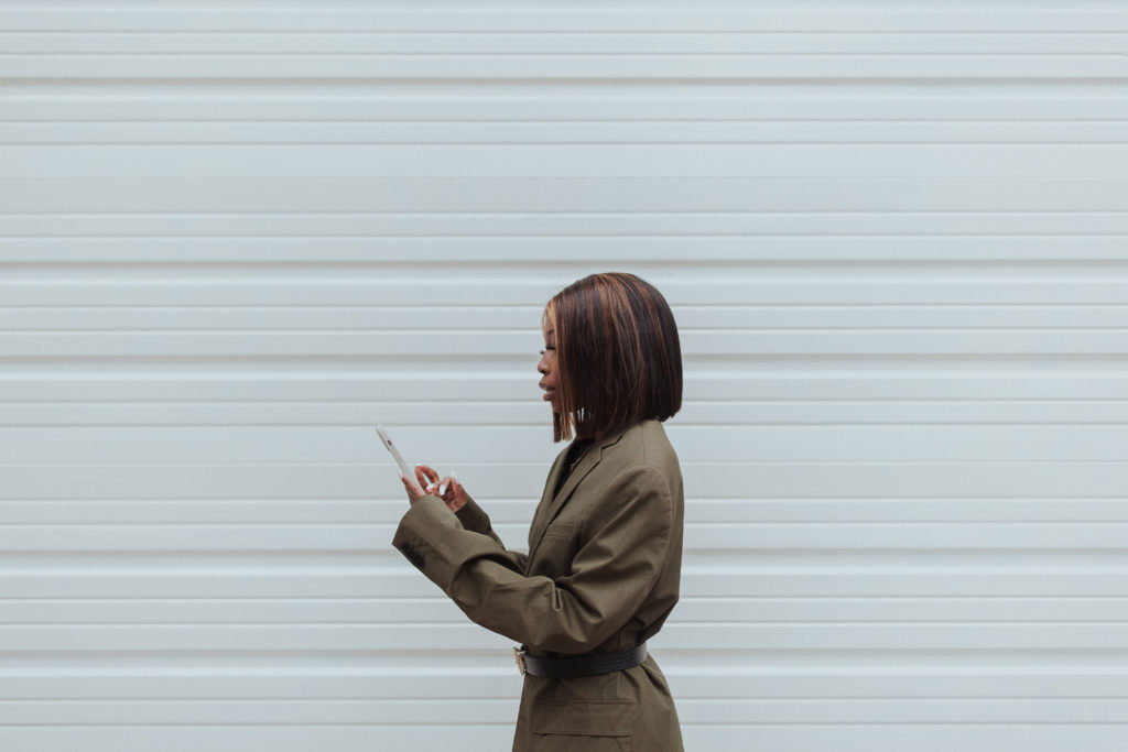 How to Pitch to Brands A creator pitching to a brand on her cellphone wearing a green blazer 